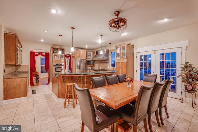 dining room featuring arched walkways, french doors, light tile patterned floors, recessed lighting, and baseboards