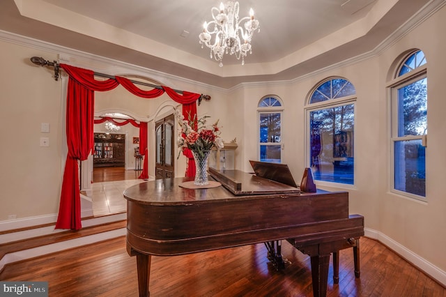 interior space with baseboards, a tray ceiling, wood-type flooring, and an inviting chandelier