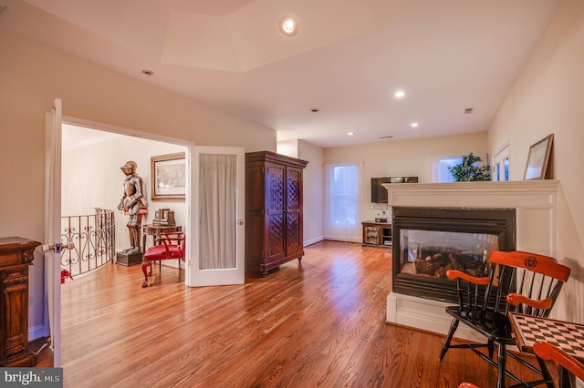 sitting room featuring recessed lighting, baseboards, wood finished floors, an upstairs landing, and a multi sided fireplace