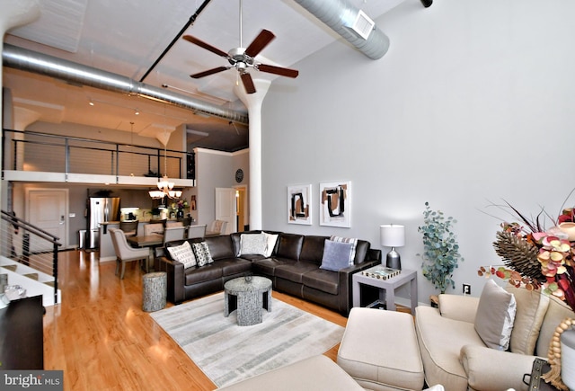 living room with wood finished floors, a towering ceiling, and a ceiling fan