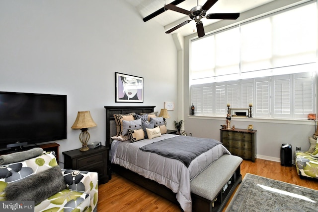 bedroom with ceiling fan, beamed ceiling, baseboards, and wood finished floors