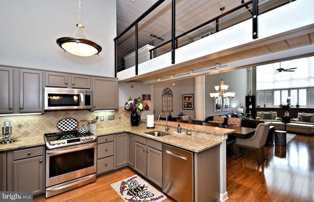 kitchen with open floor plan, stainless steel appliances, a sink, and gray cabinetry