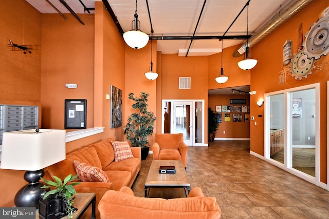 living area with a high ceiling, baseboards, visible vents, and mail area