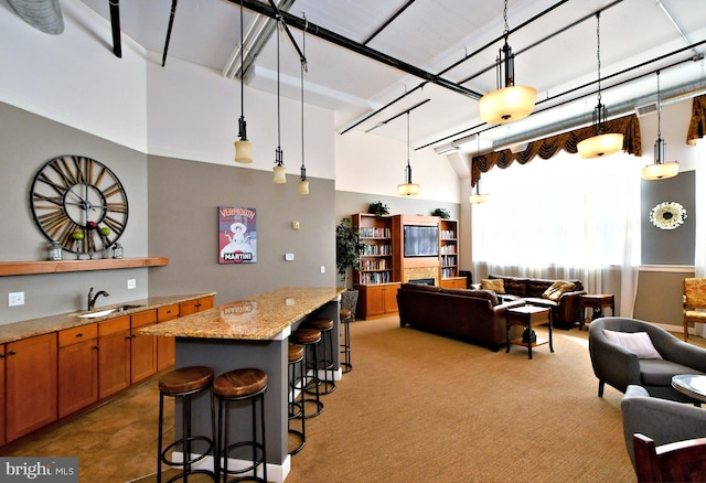 kitchen featuring a kitchen island, open floor plan, a kitchen breakfast bar, light stone countertops, and a sink