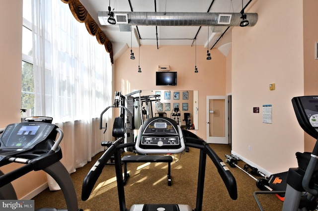 workout area featuring a high ceiling, visible vents, and baseboards