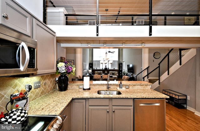 kitchen featuring a peninsula, wood finished floors, a sink, tasteful backsplash, and stainless steel microwave