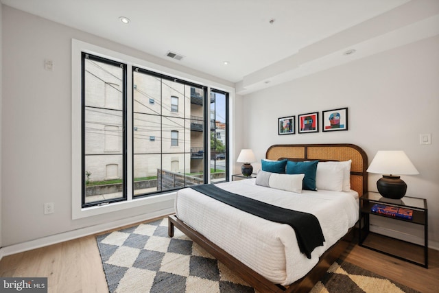 bedroom with multiple windows, wood finished floors, visible vents, and baseboards