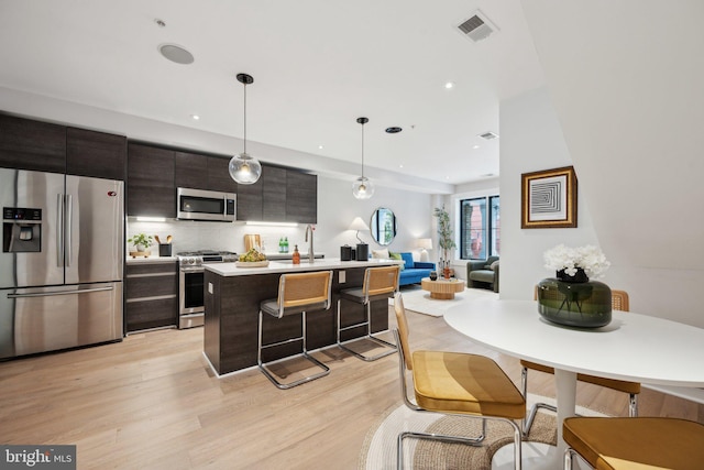 kitchen with a sink, visible vents, light countertops, appliances with stainless steel finishes, and light wood-type flooring