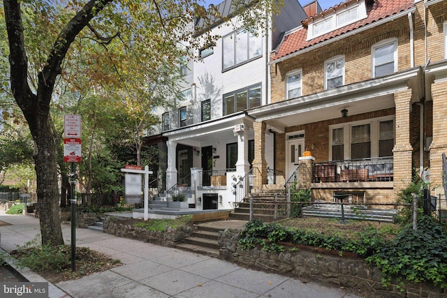 view of front of property with a fenced front yard, a porch, and brick siding