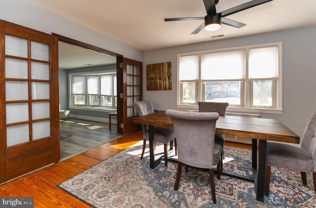 dining area featuring a ceiling fan, wood finished floors, visible vents, and baseboards