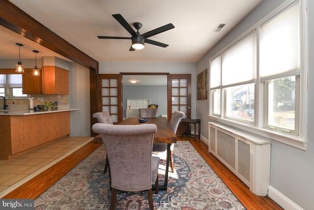 dining room with light wood-type flooring, radiator heating unit, and visible vents