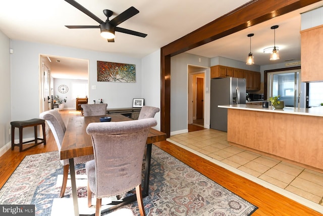 dining space featuring light wood-style floors, baseboards, and a ceiling fan