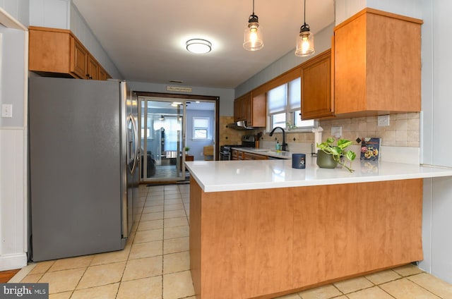 kitchen featuring light tile patterned floors, a sink, black stove, stainless steel fridge, and a peninsula