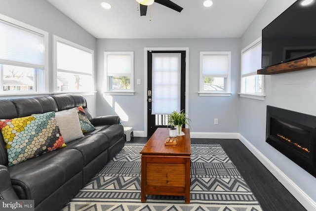 living area featuring ceiling fan, recessed lighting, dark wood-type flooring, baseboards, and a glass covered fireplace