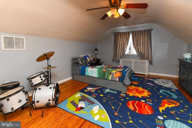 bedroom featuring lofted ceiling, visible vents, radiator heating unit, wood finished floors, and baseboards