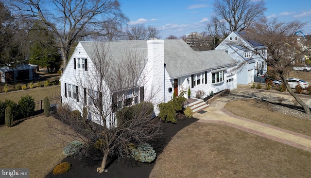 view of front facade with driveway, a chimney, and fence