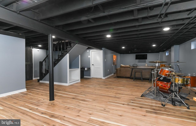 finished below grade area with stairs, baseboards, and wood finished floors