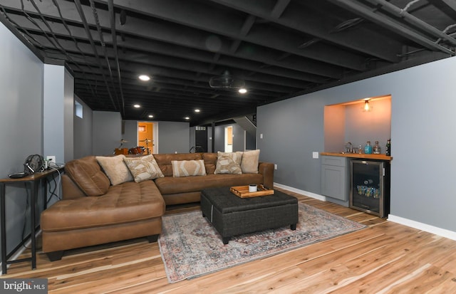 living area with a bar, wine cooler, baseboards, and wood finished floors