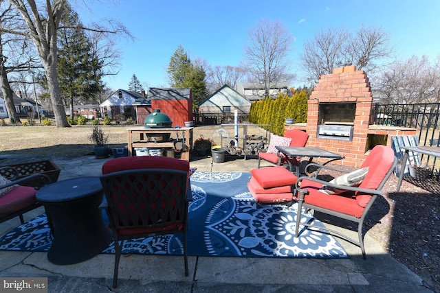 view of patio featuring an outdoor brick fireplace, fence, and area for grilling