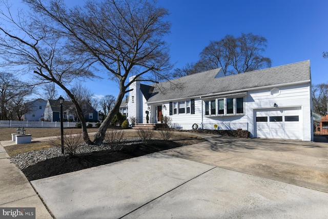 view of front of home featuring a garage, concrete driveway, roof with shingles, and fence