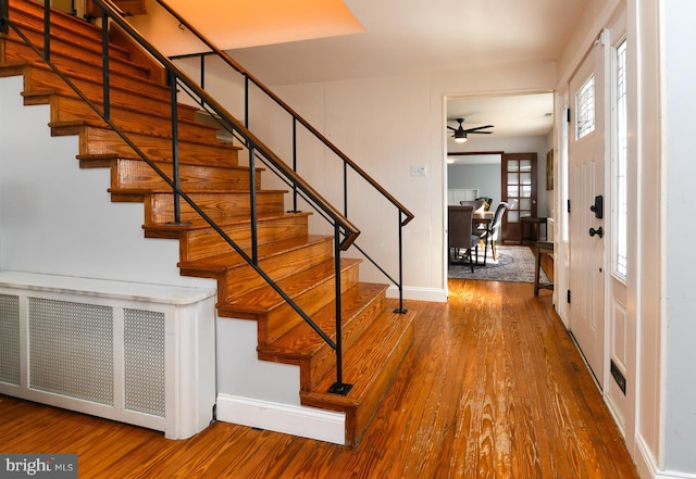 foyer entrance with a ceiling fan, stairway, baseboards, and wood finished floors