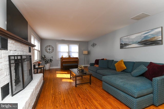 living area featuring visible vents, a fireplace, baseboards, and wood finished floors