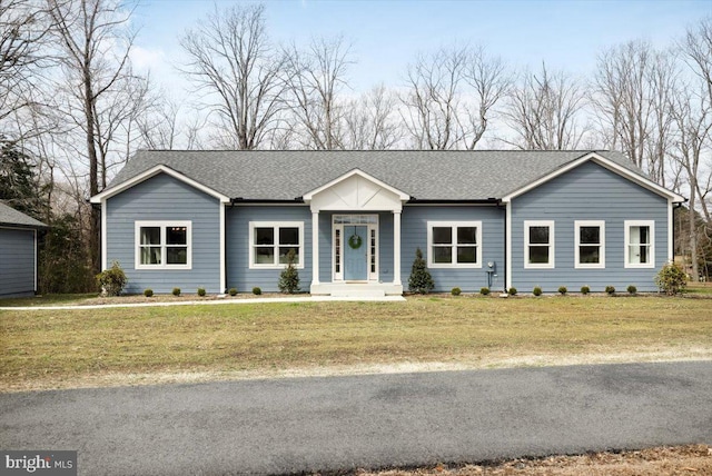 ranch-style home featuring a shingled roof and a front yard