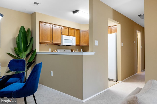 kitchen with baseboards, visible vents, white appliances, and light carpet