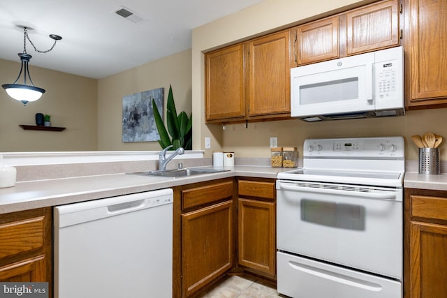 kitchen featuring brown cabinets, a sink, decorative light fixtures, white appliances, and light countertops