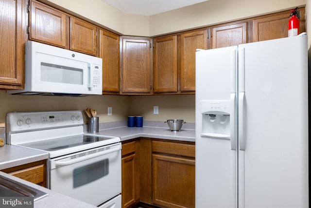 kitchen with white appliances, brown cabinets, and light countertops