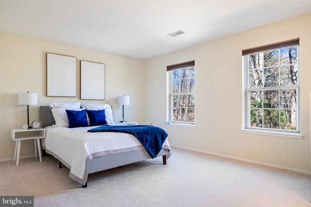 bedroom with multiple windows, visible vents, and light carpet