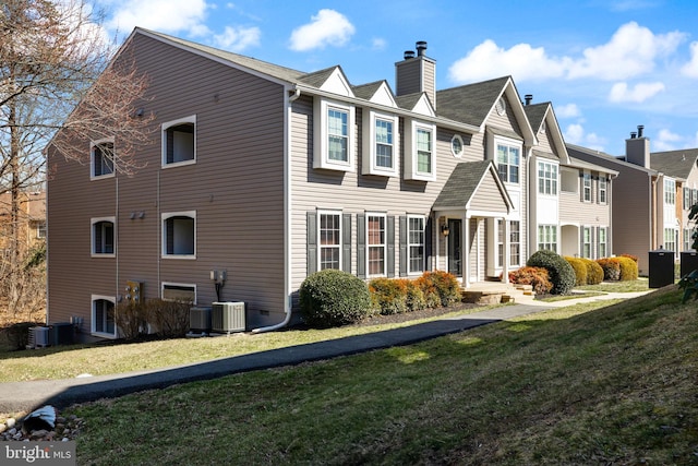 view of side of home featuring cooling unit, a lawn, a residential view, and a chimney