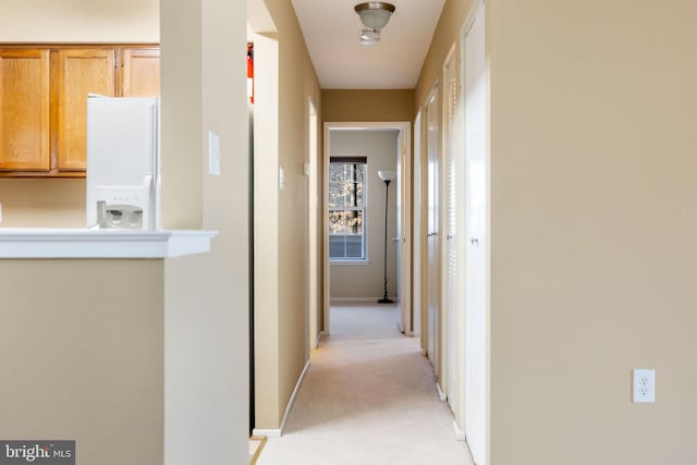 hall featuring baseboards and light carpet