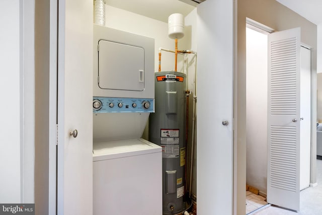 clothes washing area featuring stacked washer and clothes dryer, laundry area, and water heater