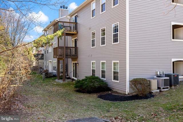 view of side of property with a balcony, a chimney, and central AC