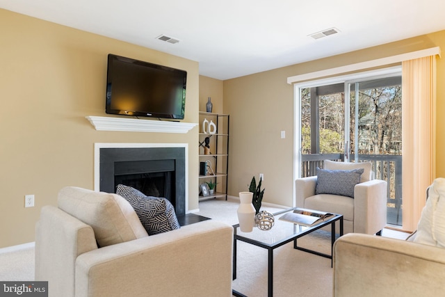 living room featuring visible vents, a fireplace with flush hearth, carpet, and baseboards