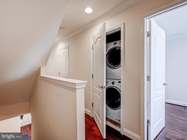 washroom featuring stacked washer and dryer, laundry area, baseboards, ornamental molding, and dark wood finished floors