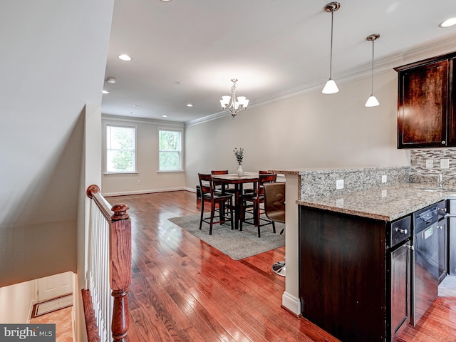 kitchen with crown molding, dark brown cabinetry, light wood-style flooring, and decorative backsplash