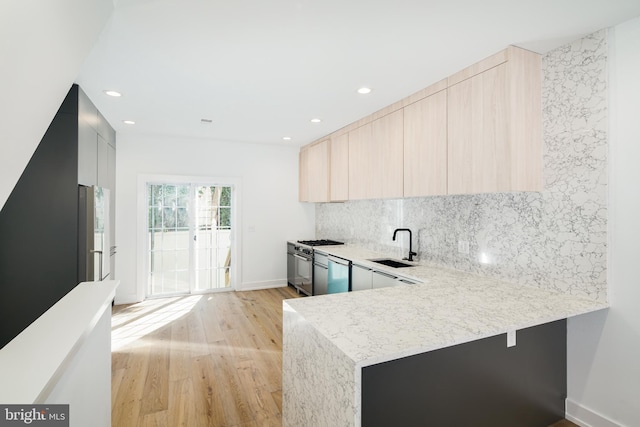 kitchen with backsplash, light wood-style floors, a sink, modern cabinets, and a peninsula