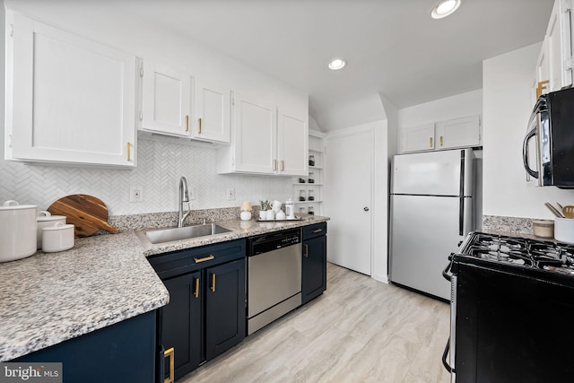 kitchen featuring gas range, freestanding refrigerator, stainless steel dishwasher, black microwave, and a sink