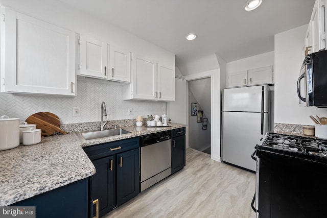 kitchen featuring tasteful backsplash, appliances with stainless steel finishes, blue cabinets, white cabinetry, and a sink