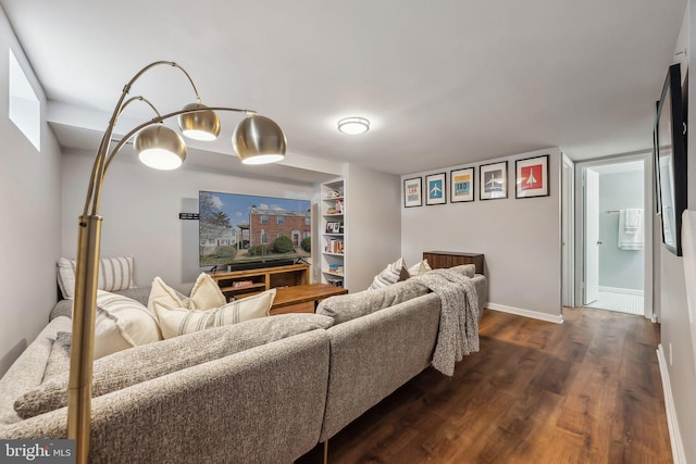 living area featuring dark wood-style floors, built in shelves, and baseboards