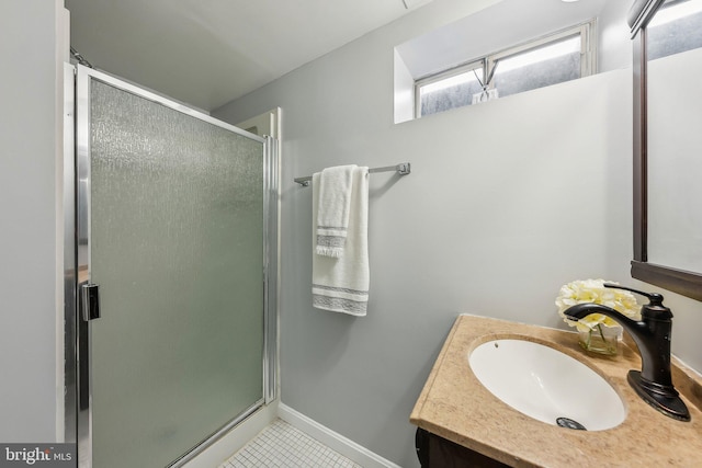 full bath featuring a stall shower, tile patterned flooring, vanity, and baseboards