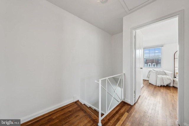 corridor featuring baseboards, an upstairs landing, and hardwood / wood-style flooring