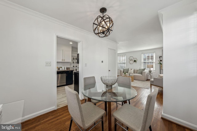 dining space featuring crown molding, baseboards, a chandelier, and wood finished floors