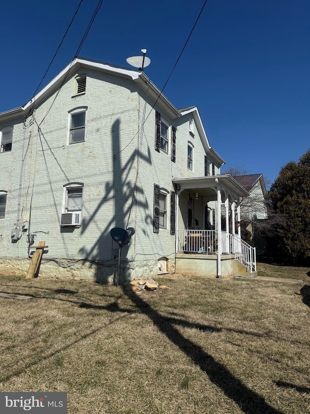 view of home's exterior with covered porch, cooling unit, a lawn, and brick siding