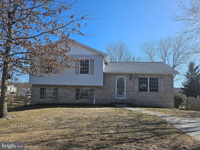 split level home with fence, a front lawn, and brick siding