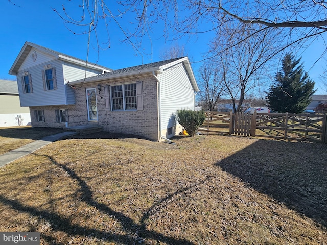 view of front of house featuring brick siding, a front yard, and fence