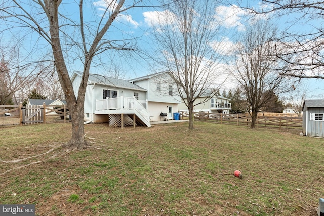 back of property with a fenced backyard, a deck, and a lawn