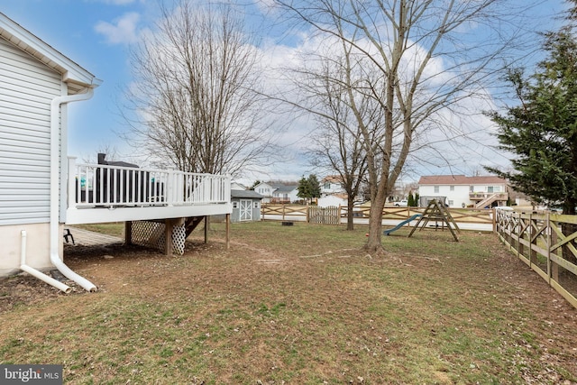 view of yard with an outbuilding, a deck, a playground, fence, and a shed